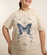 Remera color beige de corte alargado, cuello redondo y mangas cortas. Estampado frontal con una mariposa azul rodeada de elementos celestiales.