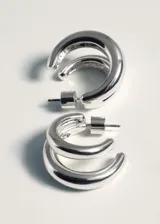Aros de diseño doble, con acabado metálico brillante en color plateado y cierre a presión.