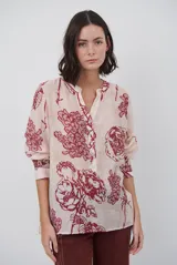 Camisa de corte holgado con estampado floral en tonos rojizos sobre base clara. Presenta cuello mao con escote en V y cierre frontal parcial con botones, además de mangas largas con puños ajustados.