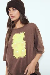 Remerón de manga corta con calce amplio y estética urbana, confeccionado con proceso de lavado que le otorga un efecto desgastado. Presenta una estampa gráfica frontal de un oso de goma en color verde.