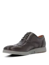 Zapato tipo Oxford con diseño brogue, confeccionado en cuero color marrón oscuro. Presenta cordones al tono y una suela de goma gris con diseño deportivo.