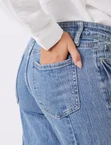 Jean recto de mujer, color azul claro, con pretina con pasadores, botón y cierre. Cuenta con bolsillos delanteros y traseros, y costura lateral asimétrica.