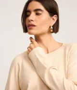 Suéter de punto color marrón chocolate, con cuello redondo y mangas largas con puños acanalados. Presenta un diseño básico y versátil de corte recto.