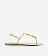 Sandalia plana color dorado, con diseño de tiras finas y aplicación de pedrería decorativa en la parte central. Cuenta con cierre de hebilla lateral ajustable.