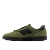 Championes New Balance modelo NM440, color verde oliva con detalles en negro y costuras naranjas. Presentan una silueta de perfil bajo, puntera reforzada y suela de goma negra.