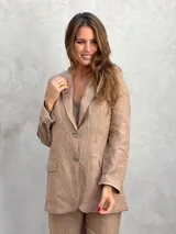 Blazer de lino color beige con finas rayas verticales oscuras. Presenta solapas de muesca, dos botones frontales y bolsillos de parche en la parte inferior. El borde de las solapas y los puños tiene un ribete oscuro contrastante.