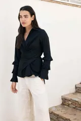 Camisa negra con corte cruzado, escote en V, mangas largas con volados y lazos laterales para ajustar.