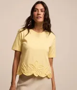 Blusa amarilla de mangas cortas con cuello redondo y bajo con flores bordadas.