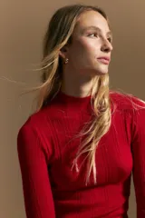 Polera de punto acanalado color rojo, con cuello alto y mangas largas, de calce ajustado al cuerpo.
