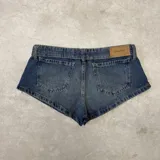 Short de denim azul de tiro bajo, con diseño clásico de cinco bolsillos, trabillas para cinto y cierre frontal con botón y cremallera.