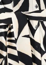 Vestido midi de viscosa con estampado de hojas en blanco y negro, sin mangas, con cuello camisero, cierre frontal de botones y cinturón a juego.