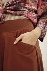 Pantalón bombacho de algodón color marrón, de corte holgado, tiro alto y puños fruncidos en los tobillos. Cuenta con bolsillos laterales.
