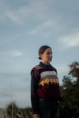 Chaleco tejido de punto con diseño de rayas horizontales y bloques de color en tonos bordó, beige, blanco y amarillo. Presenta cuello redondo y terminaciones acanaladas.