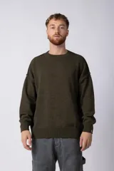 Sweater de punto grueso en color verde oliva, con diseño oversized, cuello redondo y mangas largas con puños acanalados.