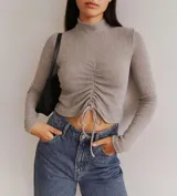 Sweater de tejido de punto acanalado, con cuello alto, mangas largas y detalle de fruncido frontal con cordón ajustable en el ruedo.