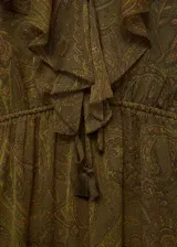 Vestido largo de tejido fluido semitransparente con estampado paisley en tonos verdes y marrones. Presenta cuello en pico con detalle de volantes, mangas largas con puños elásticos y cintura ajustable con cordón. Incluye forro interior y diseño evasé con bajo con vuelo.