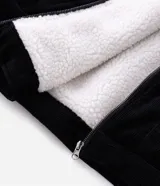 Campera de pana negra con cuello de sherpa blanco, cierre frontal por cremallera y bolsillos delanteros con solapa y botón. Presenta forro interno de sherpa para mayor calidez.