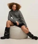 Saco largo con capucha y estampado pied de poule en blanco y negro. Tiene cuello alto, cierre con botones y cremallera, bolsillos y mangas largas.