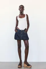 Body negro de escote redondo y tirantes anchos. Cierre inferior con botones a presión. Tejido de punto acanalado.