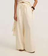 Pantalón pantalona color crudo, confeccionado en viscolino, con elástico y lazo en la cintura.