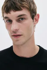 Buzo negro de punto fino con cuello redondo, mangas largas y remates acanalados en cuello, puños y bajo. Corte estándar.