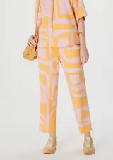 Pantalón capri de lino color rosa con estampado abstracto naranja.