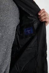 Campera negra con capucha, cierre frontal con cremallera y bolsillos laterales con botón a presión.