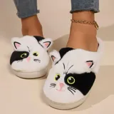 Pantuflas de diseño sin talón con forma de gato, confeccionadas en piel sintética suave. Presentan un patrón bicolor en blanco y negro con detalles bordados de ojos, nariz y bigotes, y cuentan con suela de goma antideslizante.