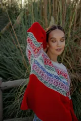 Sweater rojo de lana merino con cuello redondo y mangas largas. Presenta un canesú con diseño geométrico multicolor en tonos blanco, rojo, azul, verde y rosa.