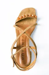 Sandalias de taco cuadrado medio, confeccionadas en gamuza color azul. Presentan tiras finas que cruzan el empeine, una pulsera ajustable al tobillo y detalle de cuentas decorativas en la tira frontal.