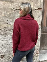 Sweater de punto grueso color borgoña con cuello alto y diseño de trenzas en el frente.
