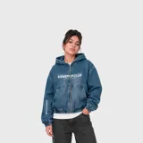 Campera de jean azul de corte oversize, con capucha, cierre frontal completo y bolsillos estilo canguro. Cuenta con estampa tipográfica en el pecho y en la manga, además de puños y dobladillo elastizados.