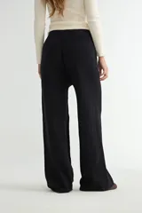Pantalón de punto color crema, de corte recto y holgado, con cintura elástica y cordón ajustable. Presenta costuras verticales decorativas a lo largo de las piernas.
