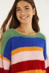 Sweater cropped de tejido de punto con acabado afelpado y diseño de rayas multicolor. Presenta cuello redondo, mangas largas y silueta amplia, combinando textura suave con un estilo vibrante y moderno.