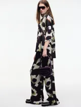 Camisa de manga corta con estampado abstracto en tonos negro, blanco y verde. Tiene cuello camisero y botones en la parte delantera.