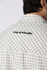 Camisa de manga corta de popelina con patrón a cuadros, calce boxy y largo a la cintura, con bolsillos y canesú cortados en diagonal.