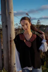 Chaleco tejido negro con cuello en V y aplique de cuero marrón.