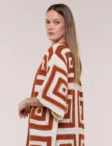Cardigan largo confeccionado en tejido de punto calado estilo crochet, de color amarillo y blanco, con diseño geométrico de cuadrados, mangas amplias tipo kimono y corte abierto al frente.