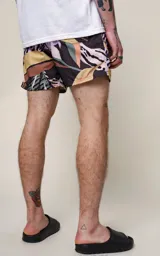 Short de baño de microfibra con estampado tropical de hojas en tonos pastel sobre fondo azul marino. Posee cintura elástica con cordón ajustable negro con inscripción repetida.