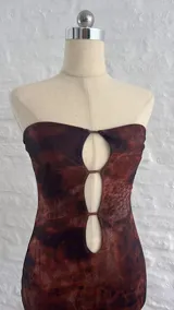 Vestido corto marrón con estampado animal print, corte ajustado, escote strapless con aberturas en el frente y breteles finos.