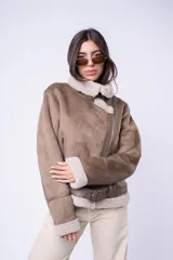 Campera tipo gamulán de corte recto, confeccionada en cuero sintético color tostado con interior y solapas de corderito sintético en tono crema. Presenta cierre frontal cruzado, bolsillos laterales con cierre y cinturón ajustable en el ruedo.