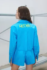 Camisa celeste de manga larga confeccionada en poplín de algodón. Tiene largo a la cintura y canesú estampado en plastisol.