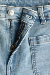 Jean de denim de algodón con tiro alto y pierna amplia de estilo wide leg. Presenta bolsillos tipo parche en la parte delantera y un lavado claro con efecto desgastado.