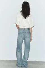 Jeans de tiro alto con corte recto, confeccionados en denim de lavado claro. Presentan bolsillos frontales tipo parche y costuras verticales decorativas en el frente.