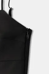Top negro de escote en pico con tirantes finos ajustables, diseño entallado y cierre lateral con cremallera.