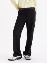 Pantalón de corte recto confeccionado en tela sastrera, con cintura de cuero vacuno, raya marcada en el centro de las piernas y bolsillos laterales.