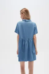Vestido corto camisero de denim celeste, con cuello camisero, mangas cortas y falda acampanada con botones frontales.