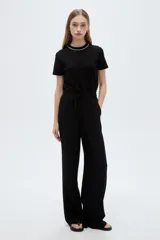 Pantalón negro de poliéster, con bolsillos laterales, tiro alto y diseño ancho.