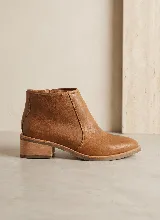 Bota corta de cuero vacuno color suela, con diseño minimalista, cierre lateral interno y taco cuadrado de madera.