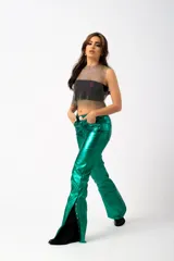 Pantalón metalizado de tiro medio en color verde, con cierre de botones en los laterales de los tobillos que permite abrocharlos o dejarlos abiertos.